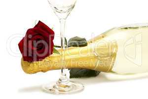 eine rote rose auf einer flasche sekt hinter einem sektglas
