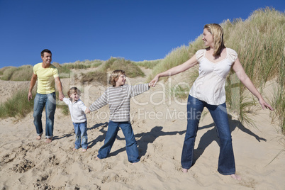 Mother, Father and Two Boys Holding Hands At Beach