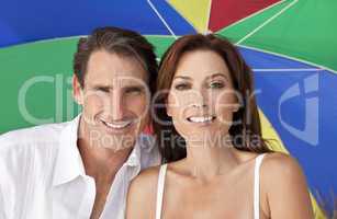 Man & Woman Couple Under Multi Colored Umbrella on Beach