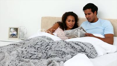 Paar liest Zeitung im Bett