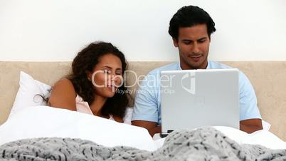 Paar mit Laptop im Bett