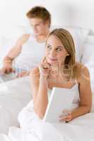 Thoughtful woman with book in bed