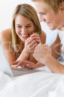 Young couple relax in bed with laptop