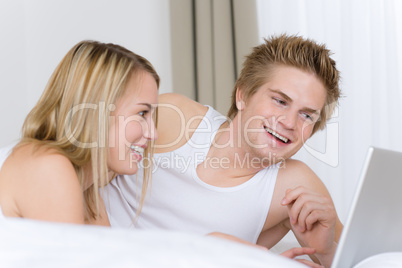 Young couple relax in bed with laptop