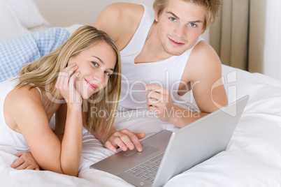 Young couple relax in bed with laptop