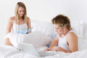 Young couple relax in bed with laptop