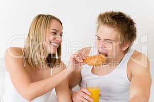 Breakfast - young couple eating croissant together