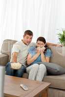 Terrified couple watching a horror movie in the living room