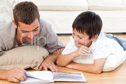 Happy father and son reading a book together on the floor