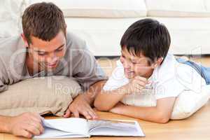 Happy father and son reading a book together on the floor