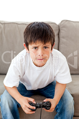 Cute boy playing video games sitting on the sofa