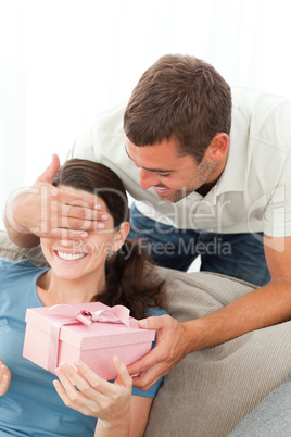Happy woman receiving a gift from her boyfriend in the living ro
