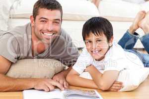 Portrait of a father and son reading a book together on the floo