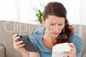 Worried woman calculating her bills in the living-room