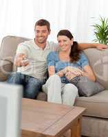 Happy man changing channel while watching television with his wi
