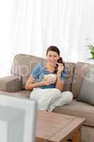 Woman laughing while watching a movie on television in the livin