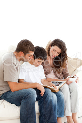 Adorable family looking at a photo album together on the sofa