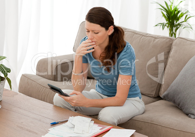 Anxious woman calculating her debts sitting in the living-room