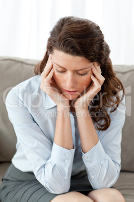 Pretty businesswoman having a headache sitting on the sofa