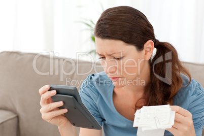 Attractive woman holding a calculator and bills while doing her