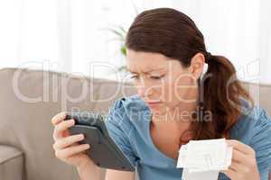 Attractive woman holding a calculator and bills while doing her