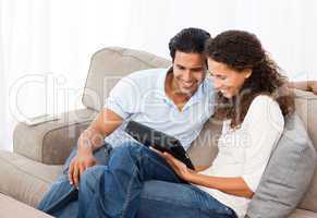 Lovely couple watching videos together sitting on their sofa