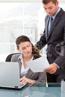 Handsome manager showing a paper to a businesswoman while workin
