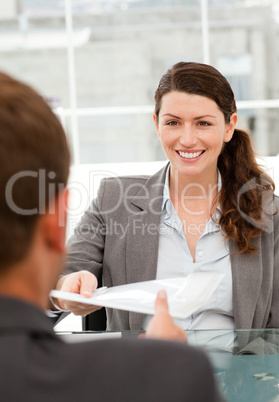 Happy businesswoman giving a paper to a male colleague during a