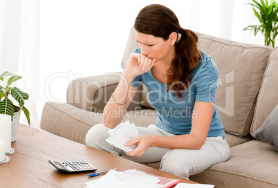 Stressed woman calculating her bills sitting on the sofa