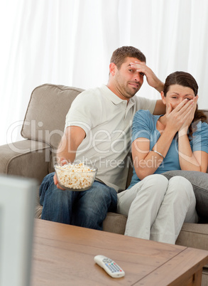 Terrified couple watching a horror movie