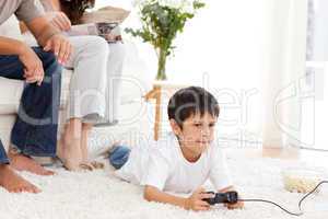 Cute boy playing video game lying on the floor at home