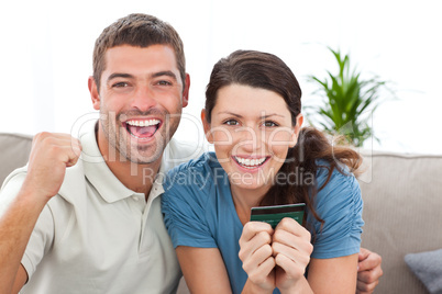 Portrait of a happy couple holding their credit card on the sofa