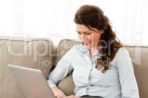 Happy businesswoman working on her laptop sitting on the sofa
