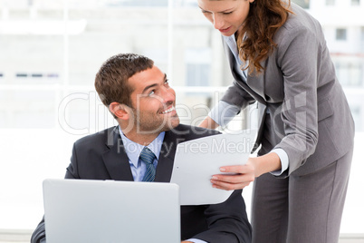 Pretty businesswoman showing a paper to her colleague working on