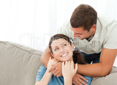 Handsome man hugging his wife while resting on the sofa