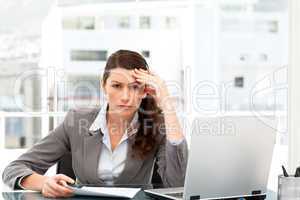 Worried businesswoman working at her desk with laptop and folder