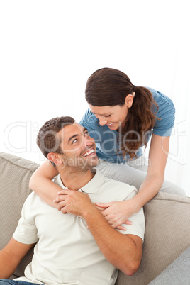 affectionate woman hugging her husband relaxing on the sofa