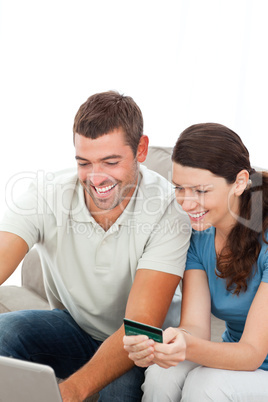 Happy couple buying online together sitting on the sofa
