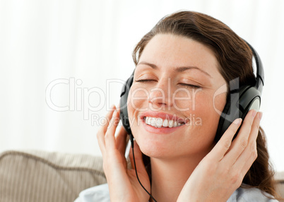 Pretty businesswoman relaxing with music sitting on the sofa