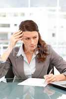 Concentrated businesswoman taking notes while working on her lap