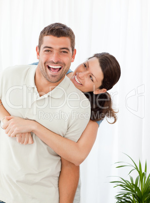 Cheerful woman hugging her husband standing in the living room