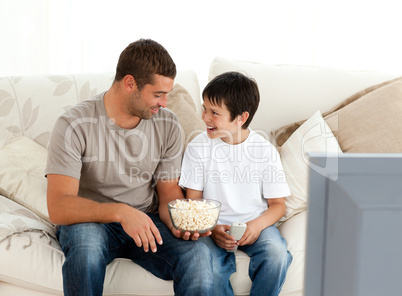 Father and son watching television while eating pop corn on the