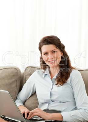 Pretty businesswoman working on the sofa with her laptop