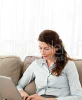 Beautiful businesswoman working on her laptop on the sofa