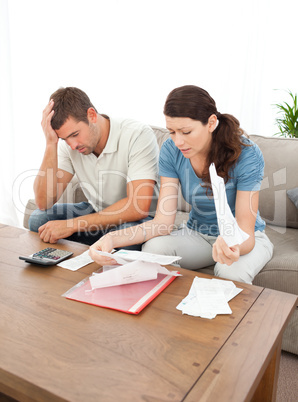 Worried couple looking at their bills in the living room