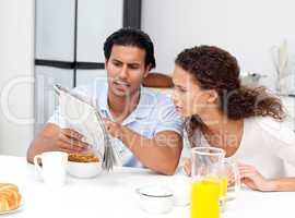 Serious man showing the newspaper to his wife during breakfast