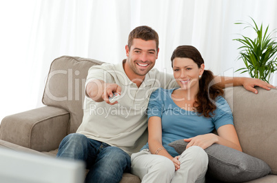 Happy man watching television with his girlfriend sitting on the