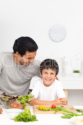 Happy father and son cutting vegetables together