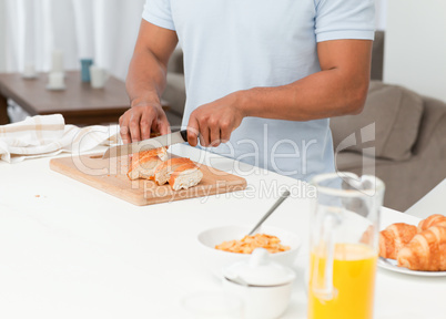 Close up of a man cutting bread during breakfast in his kitchen