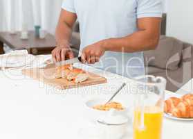 Close up of a man cutting bread during breakfast in his kitchen